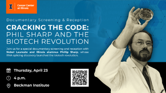 Phil Sharp in a lab coat looking at a petri dish he's holding above his head