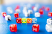 A photograph of multicolored plastic beads that have letters inscribed on them, spelling the word 'Game'