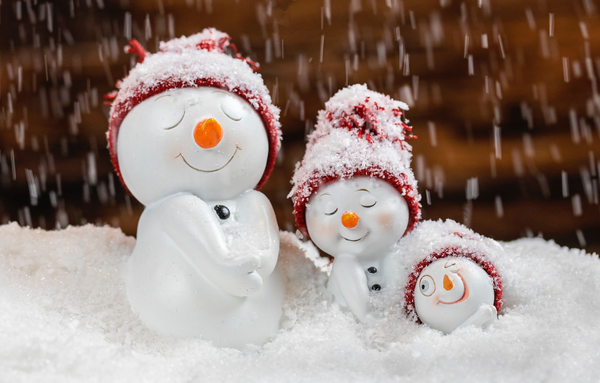 An image of three snowmen smiling, in the snow.