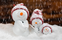 An image of three snowmen smiling, in the snow.