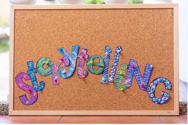 Photograph of a cork board with the word "storytelling" in colorful letters pinned to it.