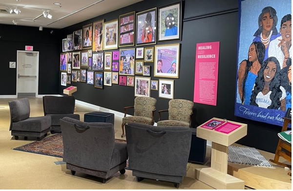 Photograph of a sitting area with four arm chairs. Portraits decorate the grey wall.