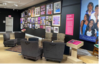 Photograph of a sitting area with four arm chairs. Portraits decorate the grey wall.