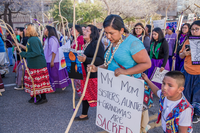 Photograph of protesters: women and children wearing colorful clothing and holding signs.