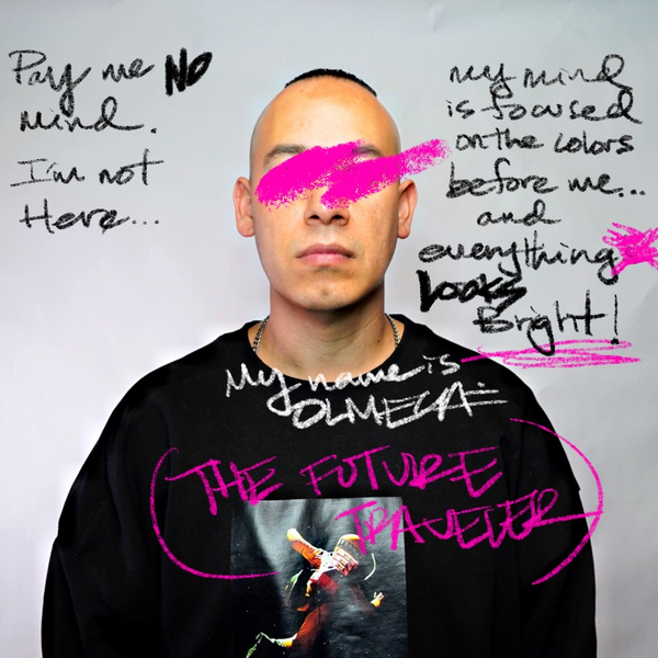 Portrait of Olmeca wearing a black sweatshirt, facing forward against a gray background. Handwritten phrases and bright pink scribbles overlay the image, including “Try me if you will,” “I’m not here…,” “no one is allowed in the wars before me,” and large pink text reading “THE FUTURE IS RACIALIZED.” A bold pink stroke obscures the person’s eyes, creating a confrontational, artistic effect.