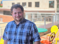 Professor Yonatan Mintz smiling, wearing a blue plaid shirt
