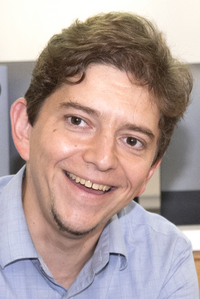 Professor Thiago Serra, wearing a blue collared shirt and smiling