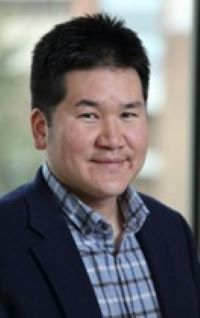 Professor Inki Kim, wearing a plaid button down shirt and blazer