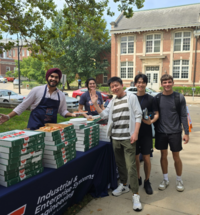 ISE student posing and serving pizza during welcome week pizza party