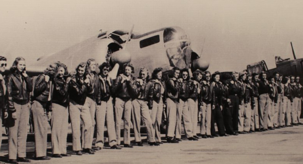 Female pilots in WWII lined up in front of plane.