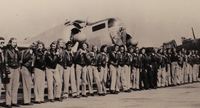Female pilots in WWII lined up in front of plane.