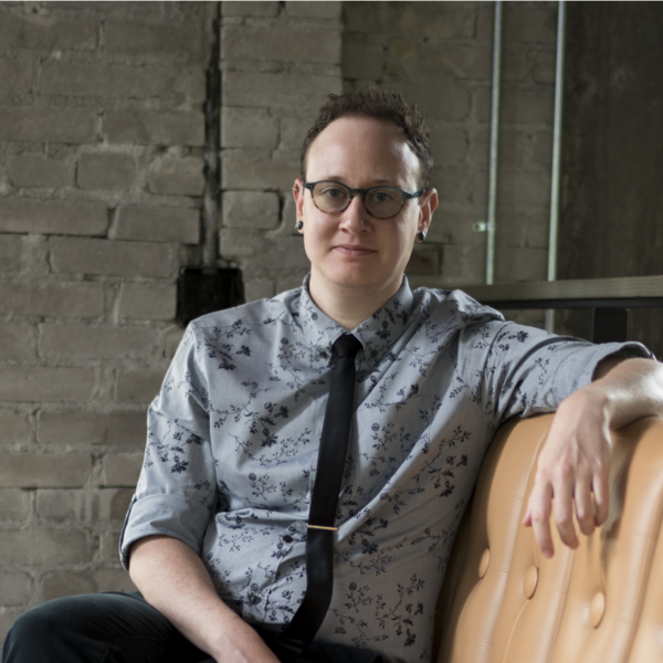 Speaker, Lex Lancaster, is sitting atop a leather chair looking straight ahead.