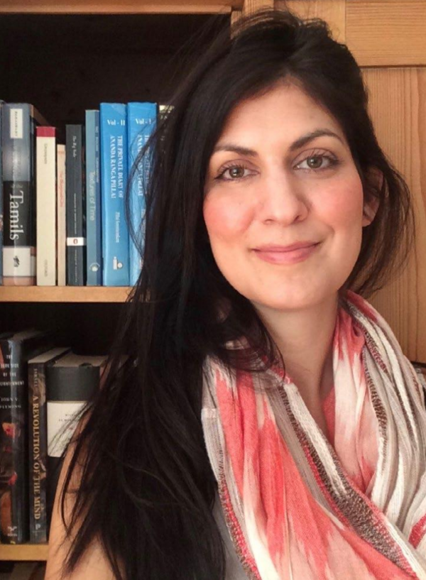 Image of Speaker Liza Oliver smiling in front of a book case