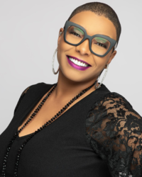 Adult woman in a black blouse and wearing large glasses facing the front with a toothy smile