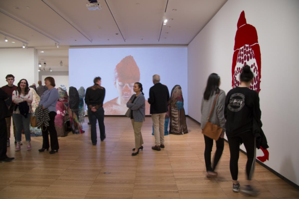 Exhibition where there are visitors of all ages admiring art projected and painted on the white walls.