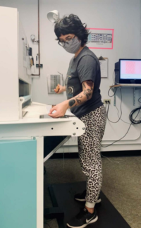 Adult observing material on a work table in a hospital-looking room.