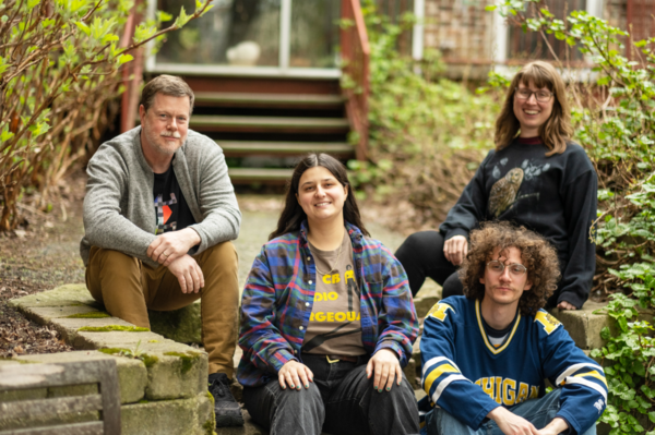 Image of four adults sitting on mossy stone steps and smiling.