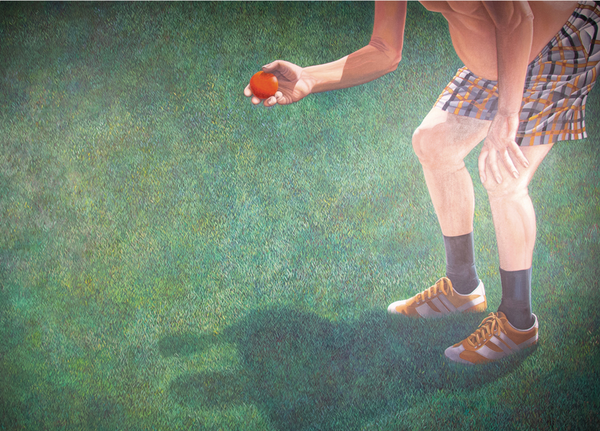 man in shorts, socks, shoes, holding a red ball, standing on grass, only the lower half of his body is visible