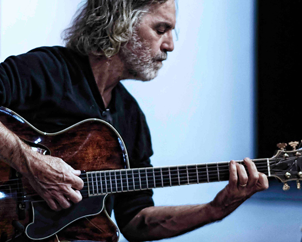Side view of musician Joe Morris holding a guitar