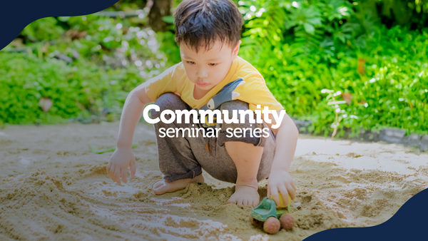 The image shows a young child wearing a yellow shirt and gray pants crouching in a sandy outdoor area, playing with a toy shovel and small objects. Bright green foliage in the background suggests a natural setting. Overlaid text reads "Community seminar series" in bold white font. The design is framed with dark blue curved borders at the top left and bottom right.