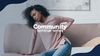 The image shows a woman sitting on a beige couch, holding her lower back with a pained expression, suggesting discomfort or back pain. She is wearing a light pink sweater and blue jeans, with a white brick wall and abstract artwork in the background. Overlaid text reads "Community seminar series" in bold white font, centered in the design. Dark blue curved borders frame the top left and bottom right corners of the image.