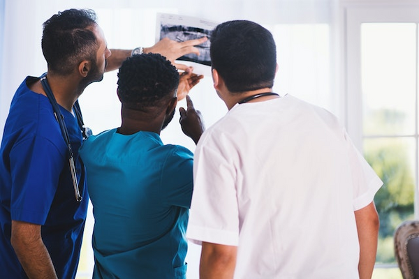 Three individuals in the medical profession looking at an x-ray