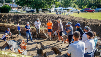 A group of people standing around an archaeological dig site.