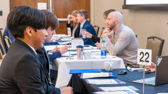 Students and professionals at table, giving interviews.