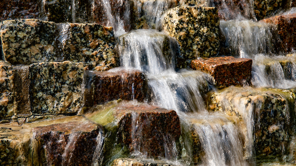 Water flowing over granite and sandstone rocks.