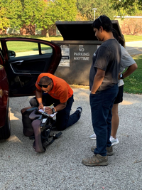 person checking a child's safety seat with two people looking on