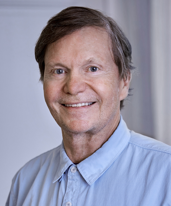 man with dark brown hair wearing a light blue shirt