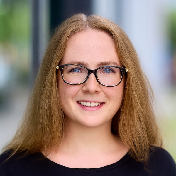 woman with long auburn hair and black glasses