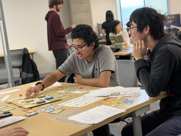 Two men at a table playing a board game.