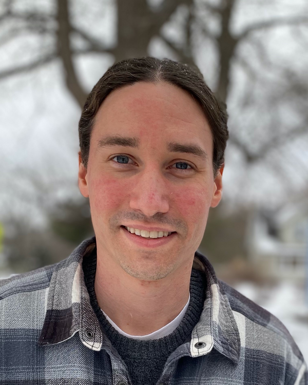 Photo of Prof. David Hershey. He has black hair, parted down the center and is smiling. He is wearing a black and white plaid shirt.