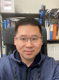 Person with short dark hair and glasses.