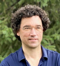 Dr. Taras Pogorelov - Man with dark curly hair and classes.